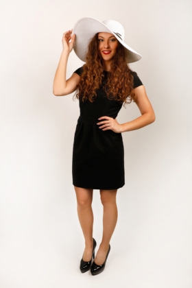 Černé pouzdrové šaty s řasením v pase, kombinace s bílým kloboukem